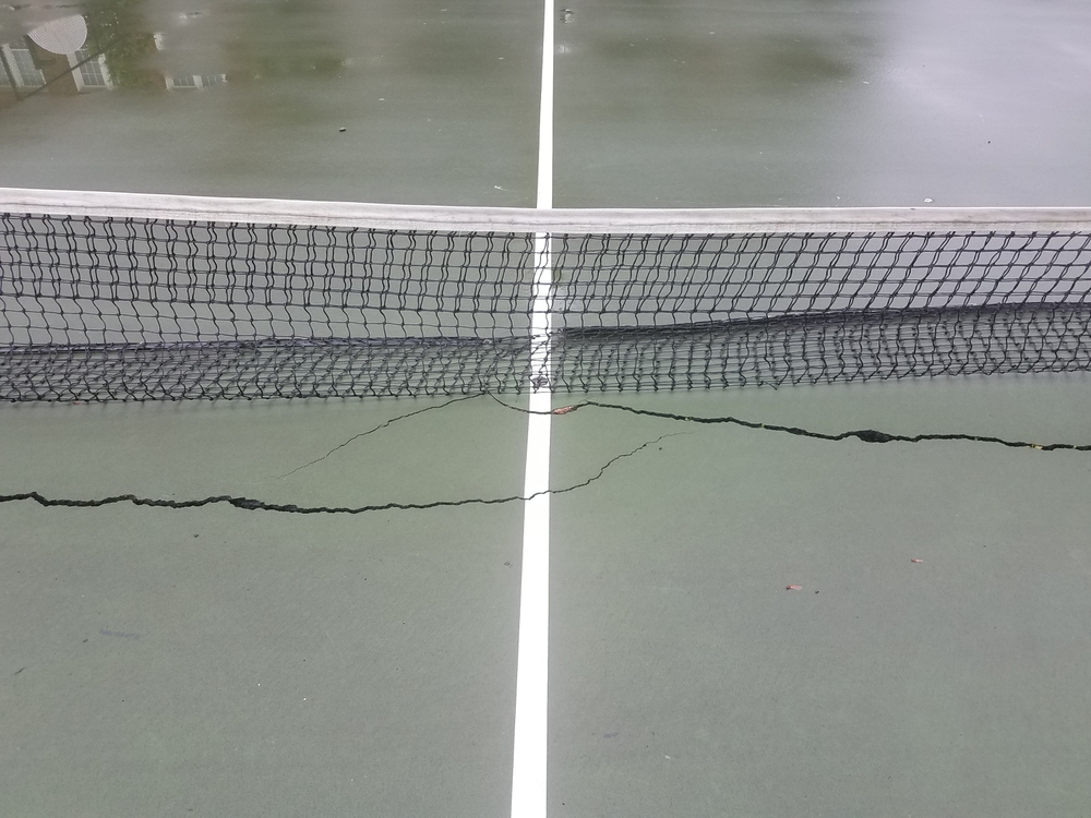long crack on a wet tennis court with net long crack or damaged on a wet tennis court with net